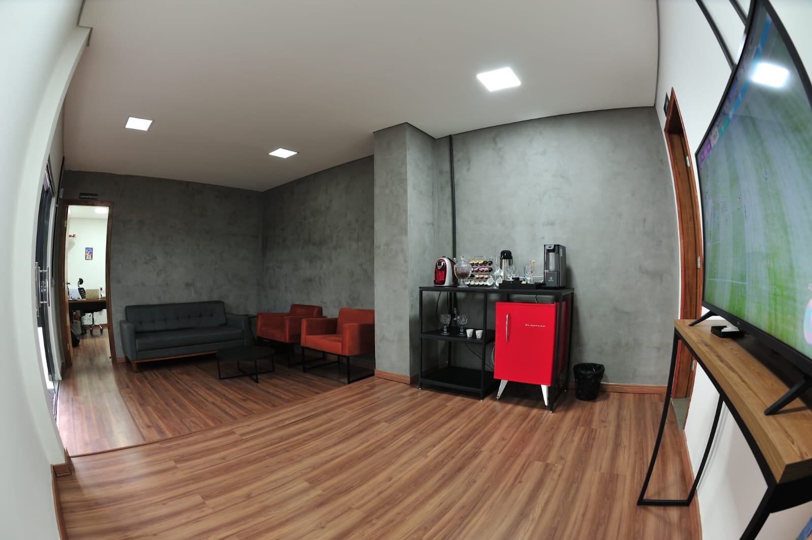 Sala de espera com poltronas, café e televisão para os clientes
